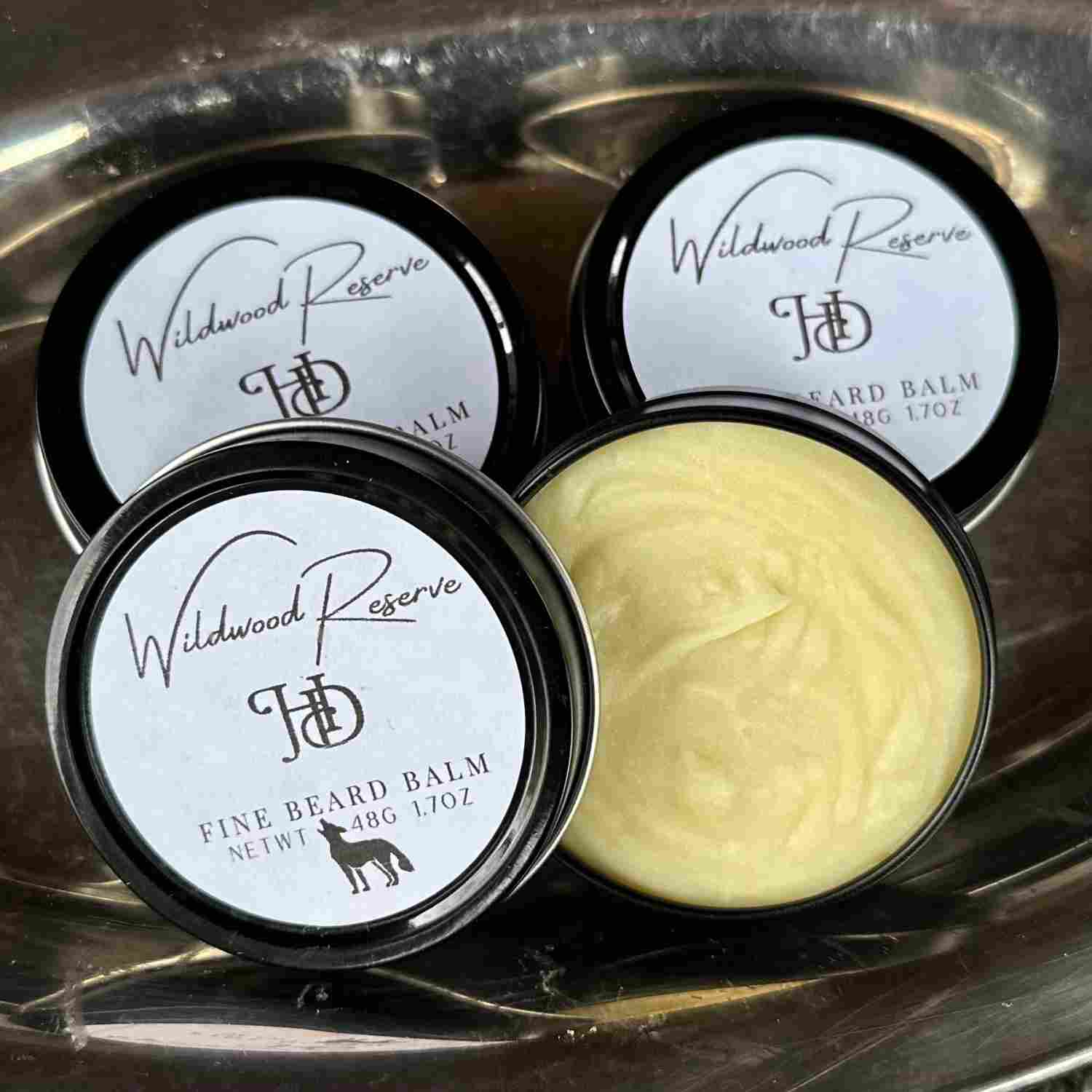 Grouping of Wildwood Reserve Fine Beard Balm with one open stainless tin on silver tray