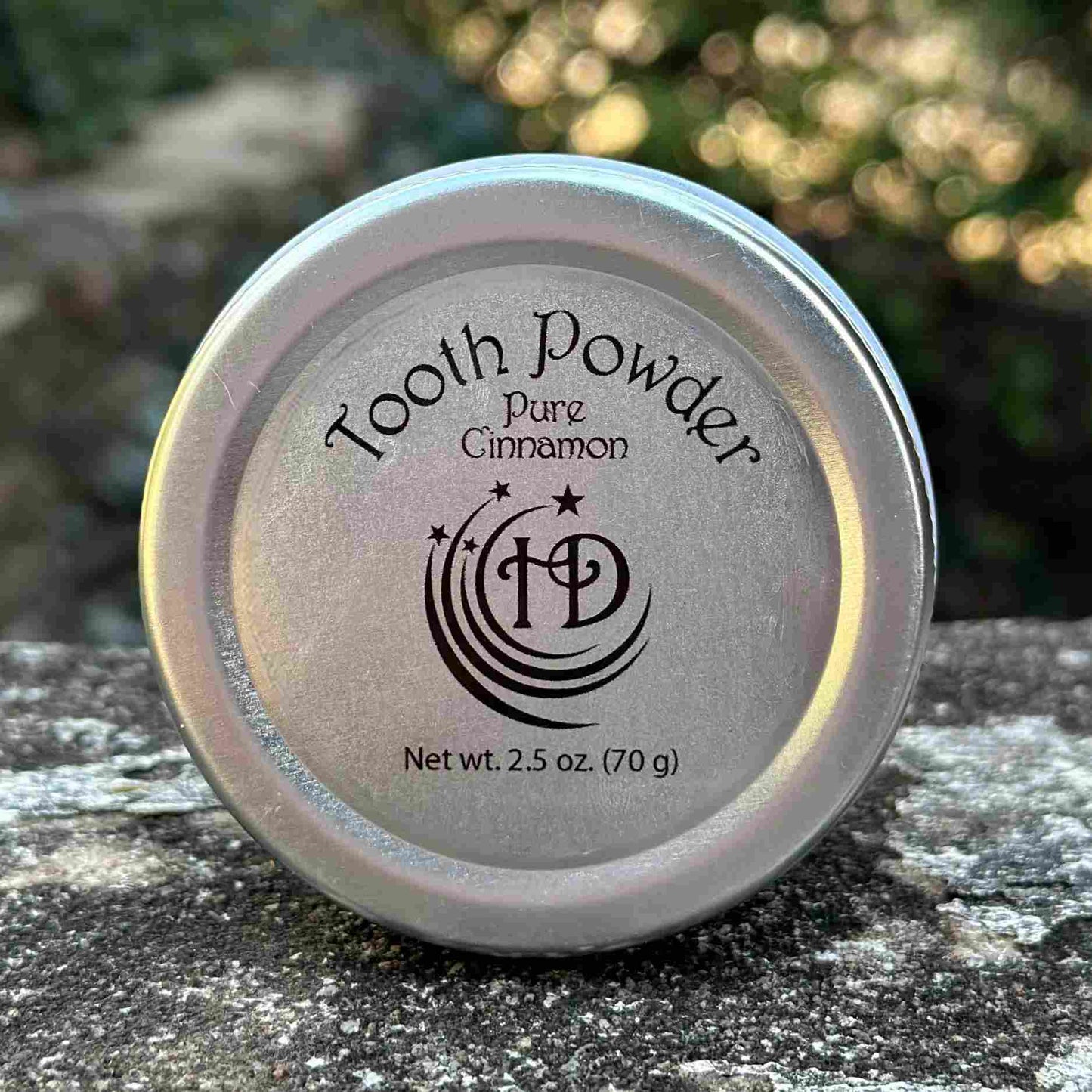 Large Cinnamon Tooth Powder Top Label displayed on stone bench